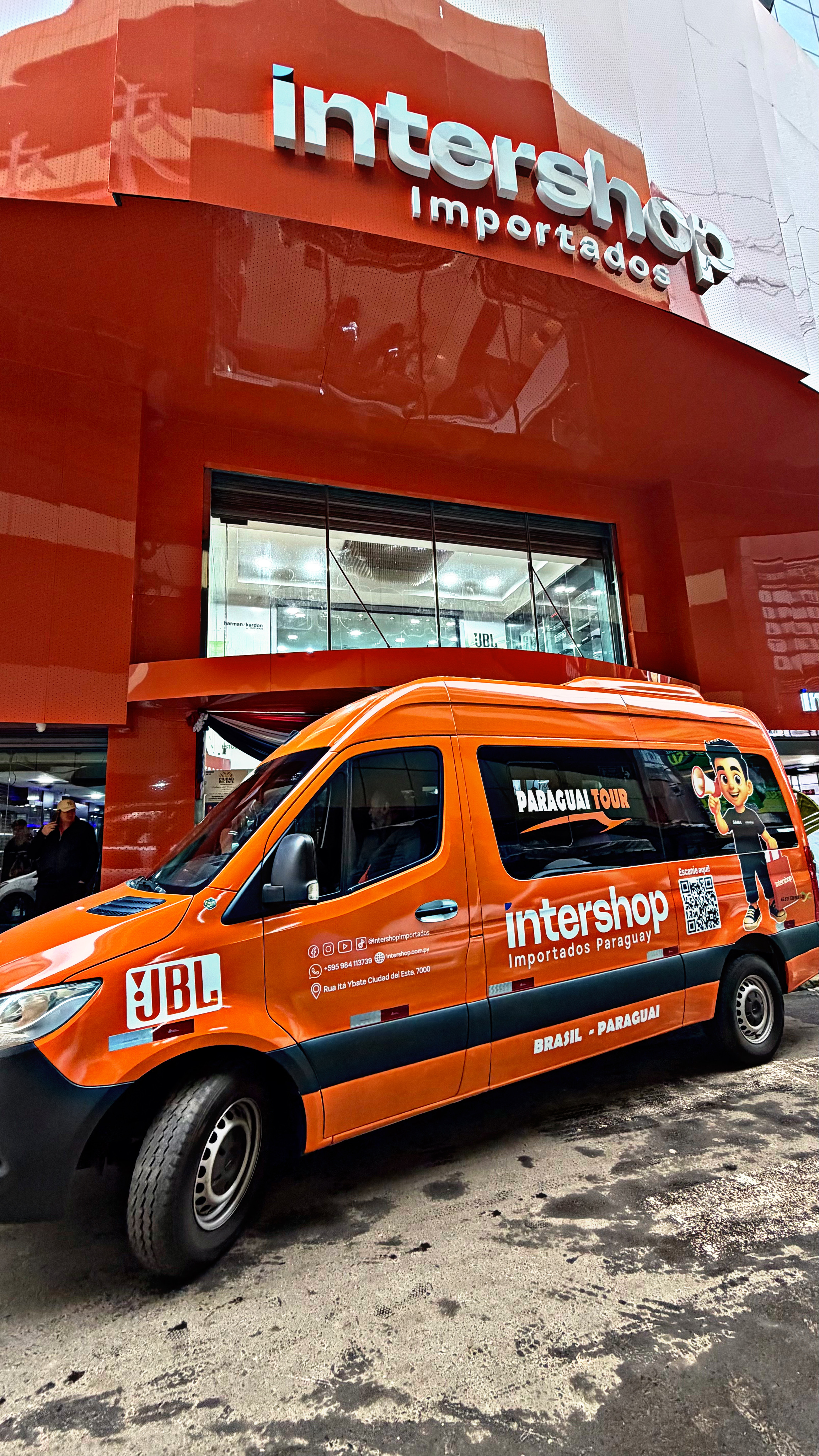 Van laranja da Paraguay Tour em frente à Intershop Importados